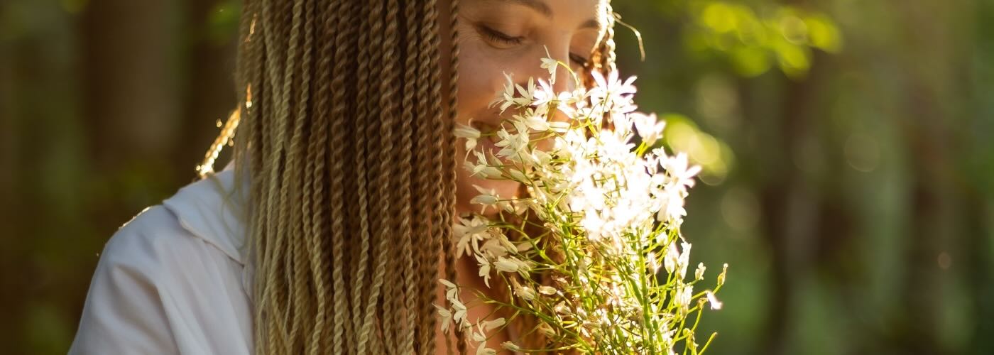 Woman outdoors sniffing white flowers