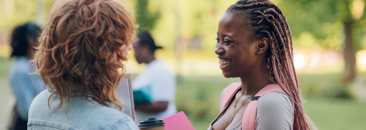 Women speaking with one another outside, laughing