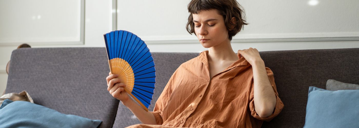 Woman seated, fanning herself