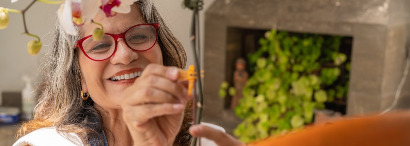 Woman clipping orchid stem, smiling